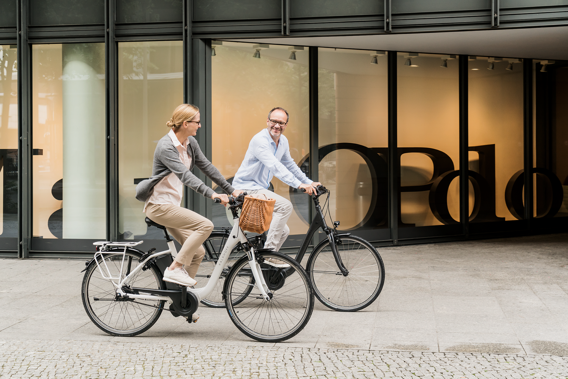 Ein Mann und eine Frau fahren auf City E-Bikes von Kalkhoff durch die Straße